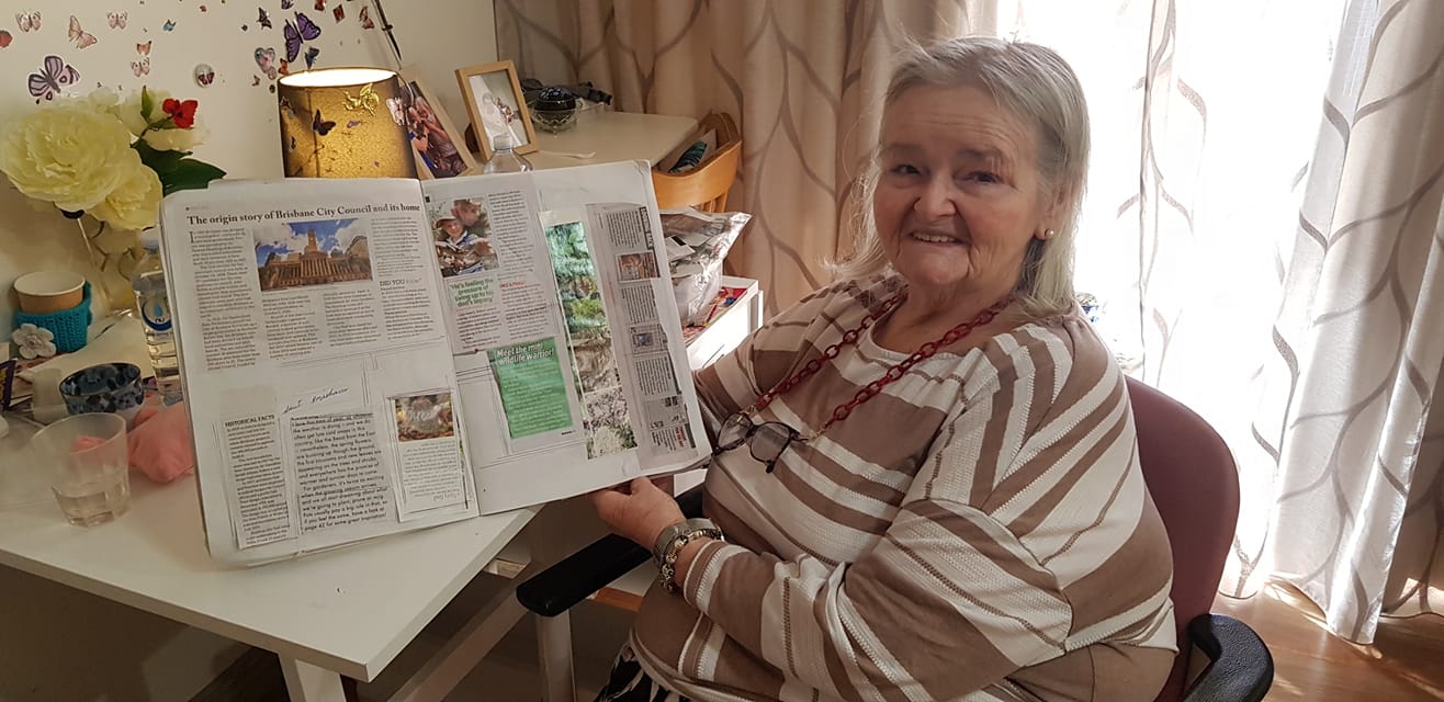 aged care resident holding up scrapbook at st vincent's care mitchelton