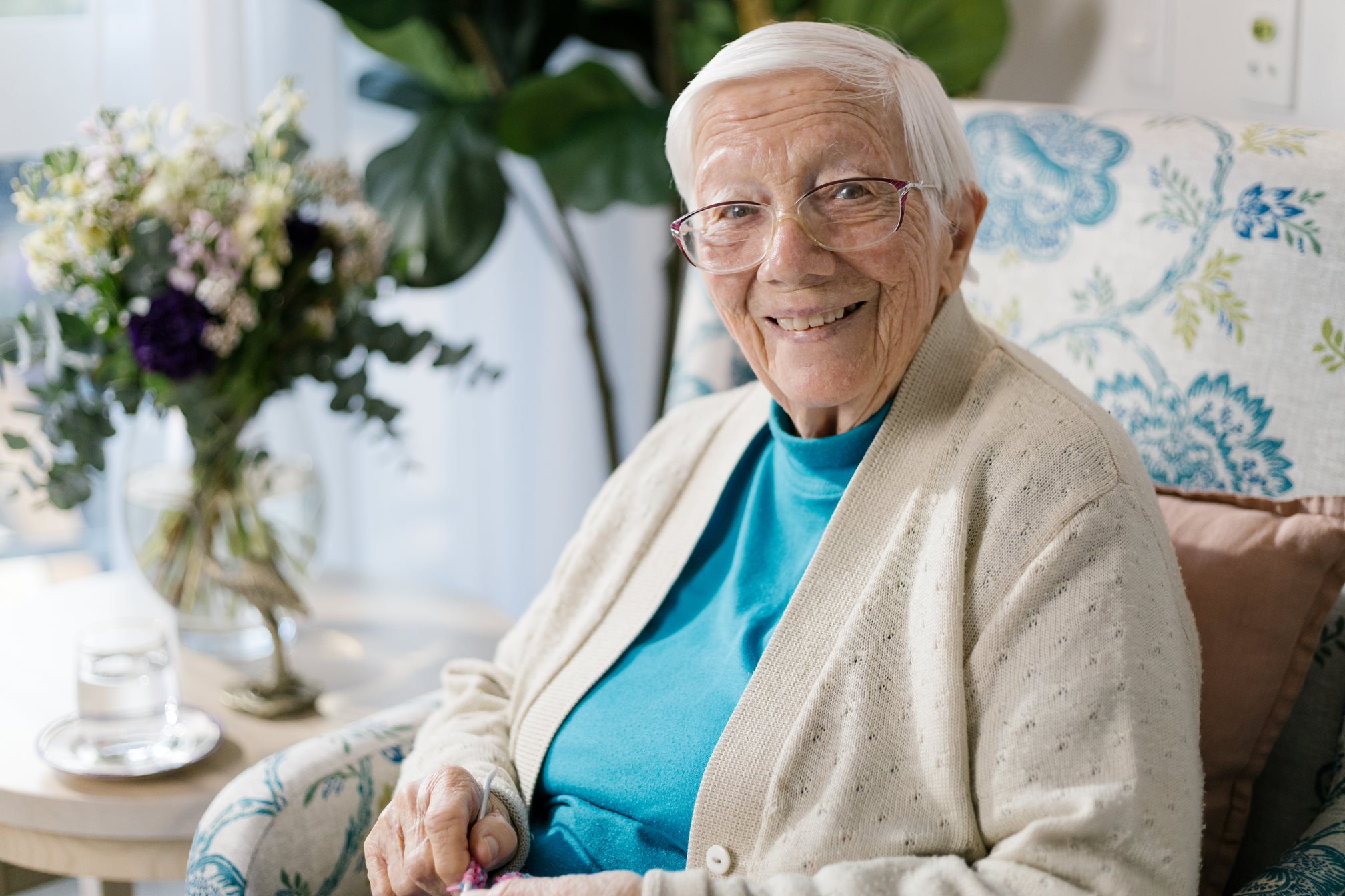 an aged care resident sitting in a lounge chair in her bedroom